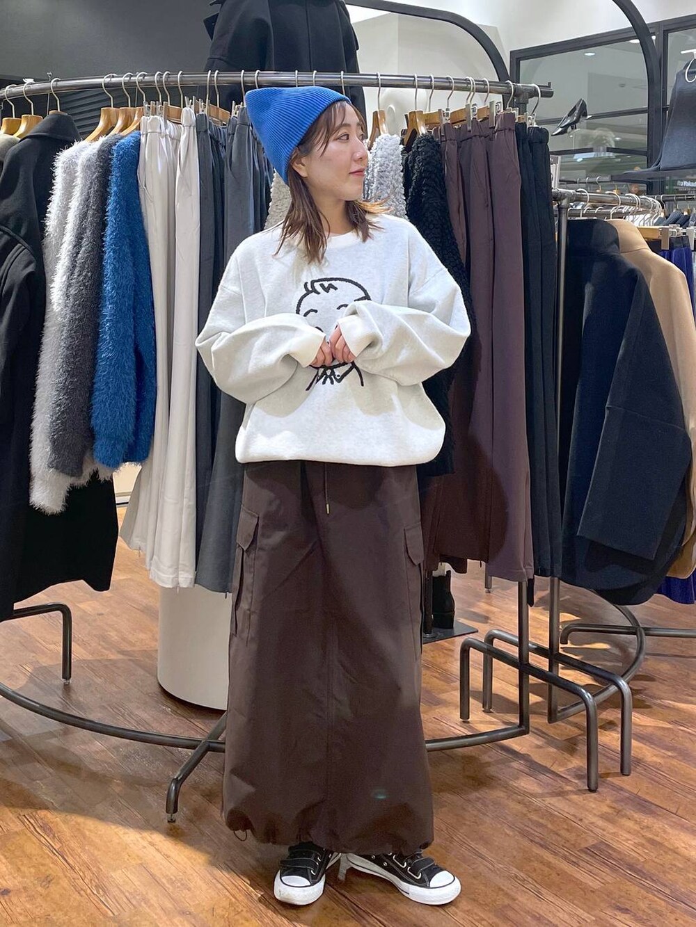 ブラウン系のスカート、ホワイト系のニット/セーター、ブルー系のニットキャップ/ビーニーを着用したレディースの冬コーディネートの2枚目の写真