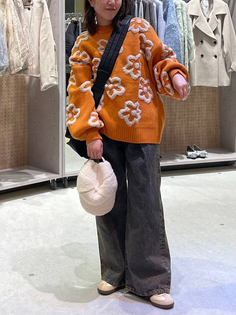 ブラック系のショルダーバッグ、ブラック系のデニムパンツ、オレンジ系のニット/セーターを着用したレディースの冬コーディネートの5枚目の写真