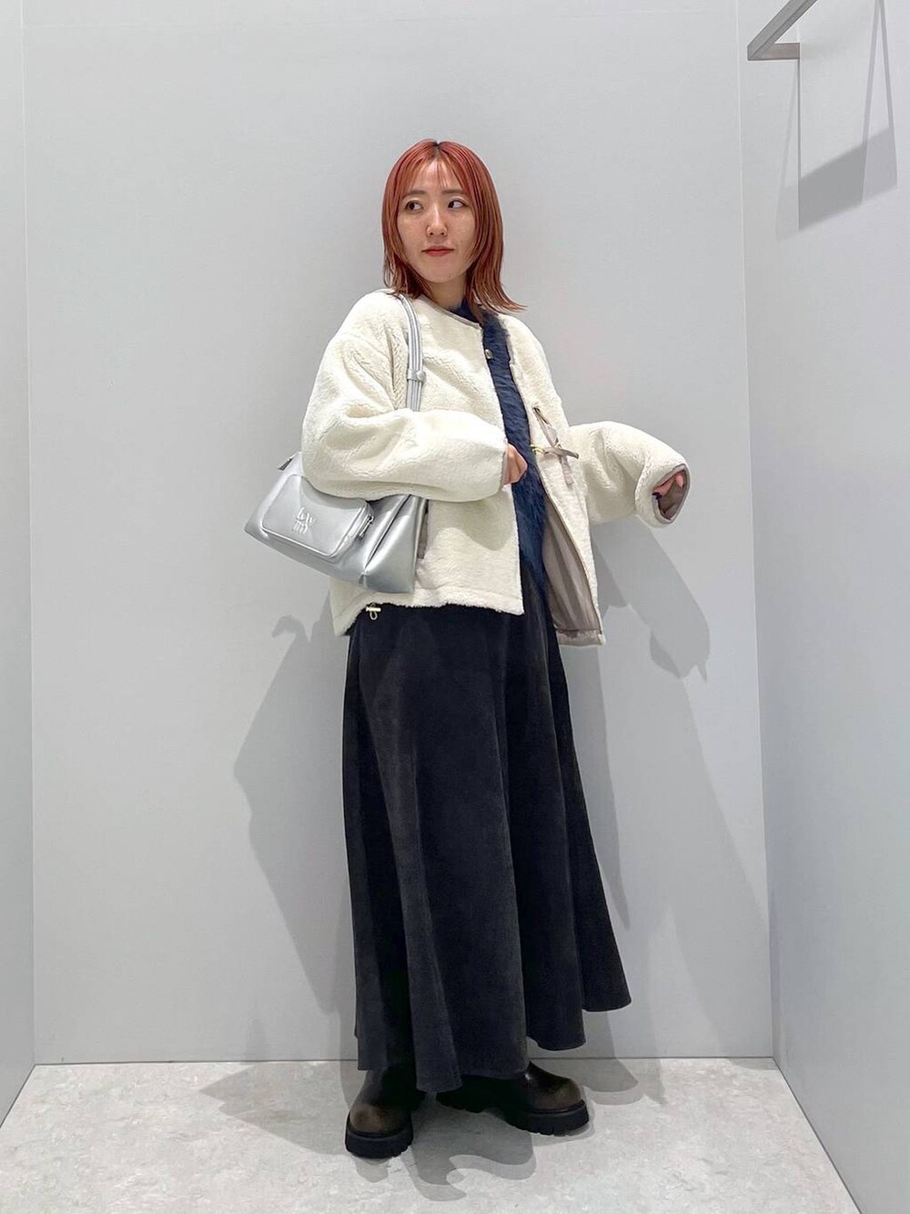 ベージュ系のブルゾン、シルバー系のショルダーバッグ、ブラック系のスカートを着用したレディースの秋コーディネートの2枚目の写真