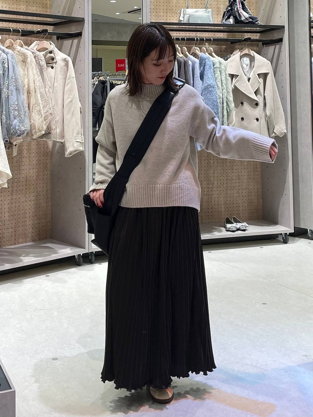 ブラック系のショルダーバッグ、ベージュ系のワンピースを着用したレディースの冬コーディネートの2枚目の写真