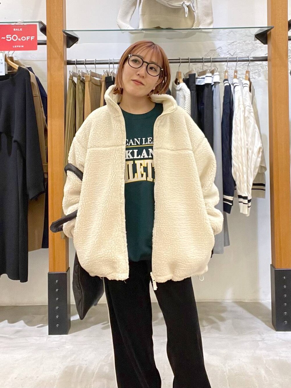 グリーン系のスウェット、ブラック系のトートバッグ、ホワイト系のその他アウターを着用したレディースの冬コーディネートの4枚目の写真