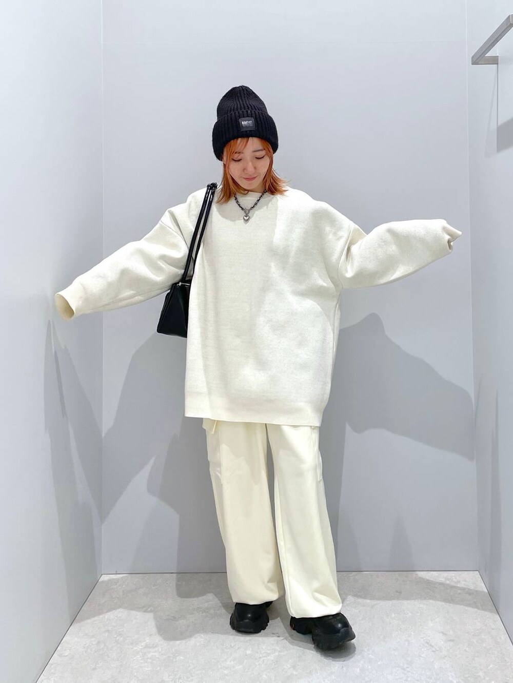 ブラック系のショルダーバッグ、ホワイト系のニット/セーター、ホワイト系のスラックスを着用したレディースの冬コーディネートの2枚目の写真