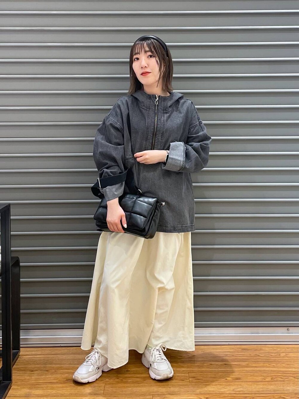 ブラック系のショルダーバッグ、ブラック系のパーカー、ホワイト系のスカートを着用したレディースの春コーディネートの2枚目の写真