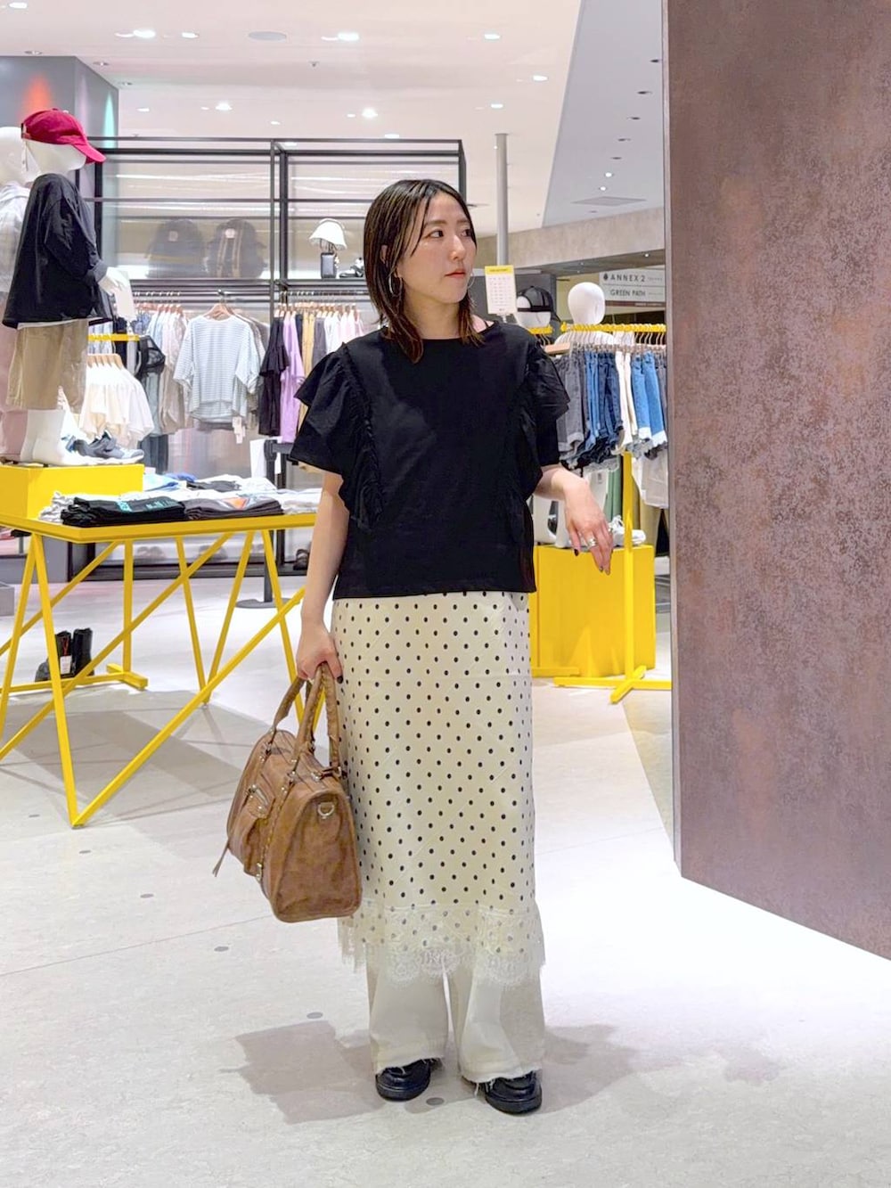 ホワイト系のデニムパンツ、ブラウン系のボストンバッグ、ブラック系のTシャツ/カットソーを着用したレディースの春コーディネートの3枚目の写真