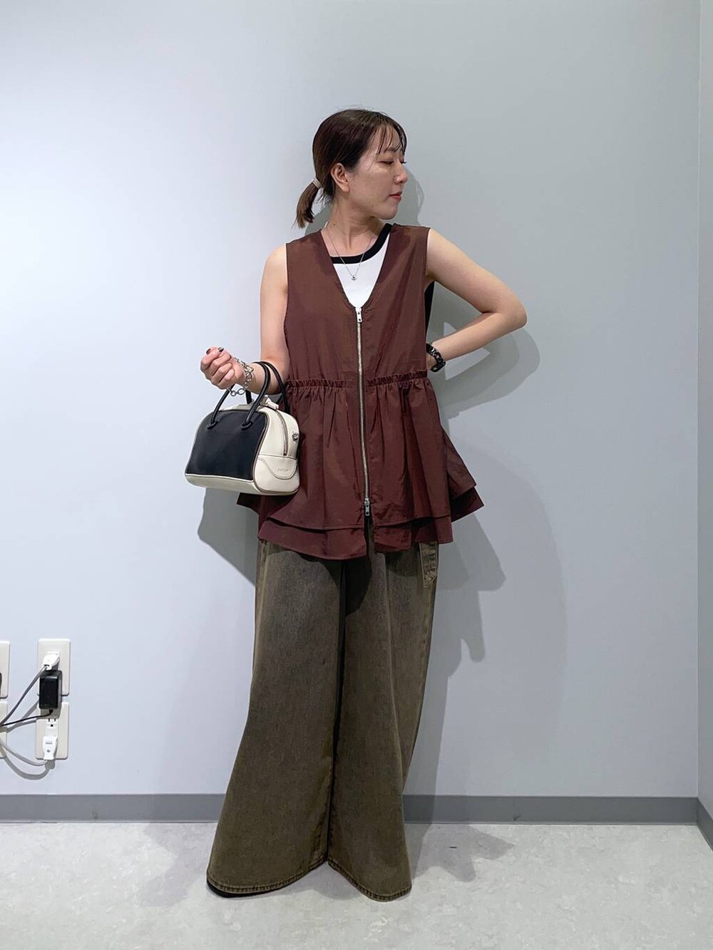 ブラウン系のベスト、ブラウン系のデニムパンツ、ブラック系のハンドバッグを着用したレディースの秋コーディネートの5枚目の写真