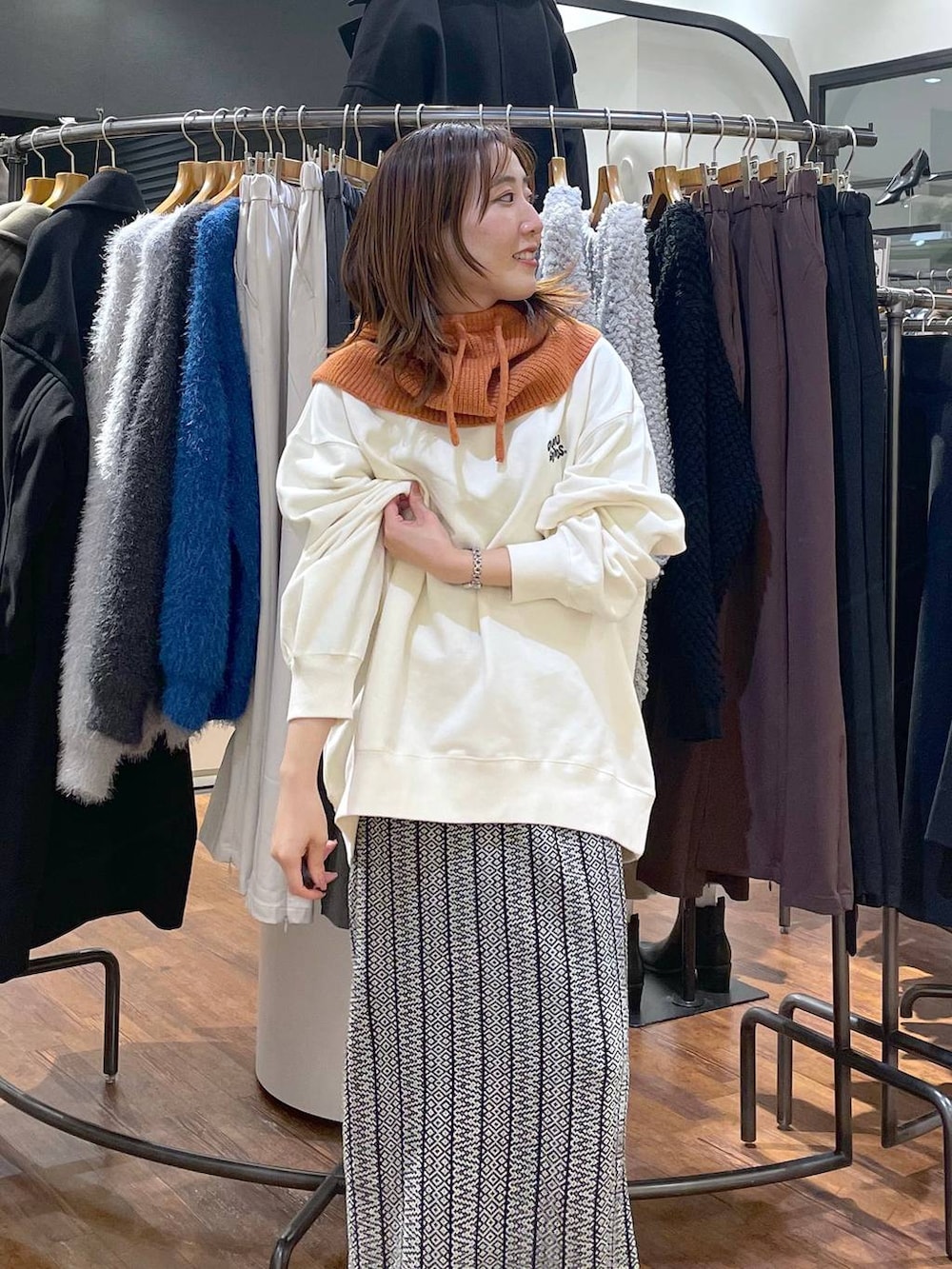 ブラック系のスカート、ホワイト系のスウェット、オレンジ系のネックウォーマー/スヌードを着用したレディースの冬コーディネートの4枚目の写真