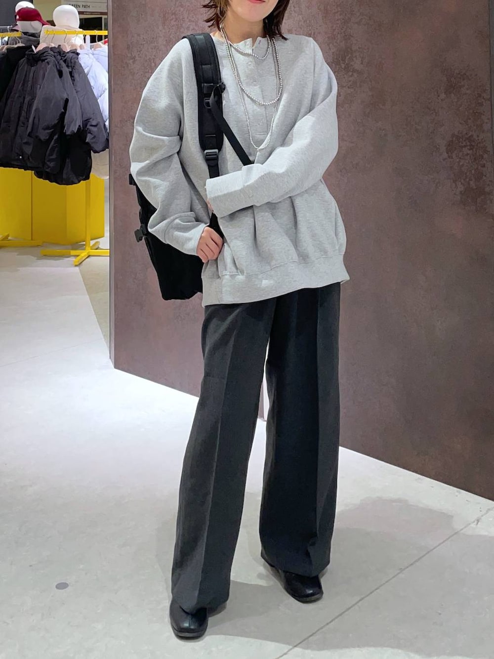 グレー系のスラックス、ブラック系のバックパック/リュック、グレー系のスウェットを着用したレディースの冬コーディネートの2枚目の写真