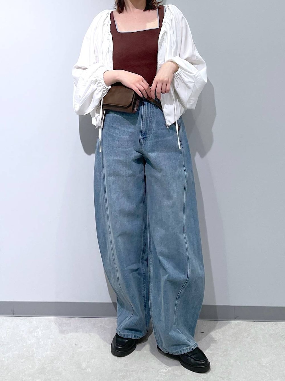 ブルー系のデニムパンツ、ブラウン系のボディバッグ/ウエストポーチ、ブラウン系のタンクトップを着用したレディースの春コーディネートの2枚目の写真