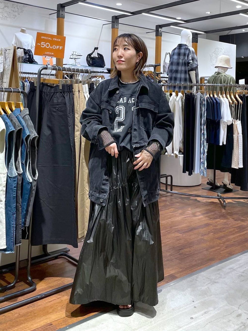 ブラック系のスカート、ブラック系のデニムジャケット、ブラック系のサンダルを着用したレディースの春コーディネートの2枚目の写真