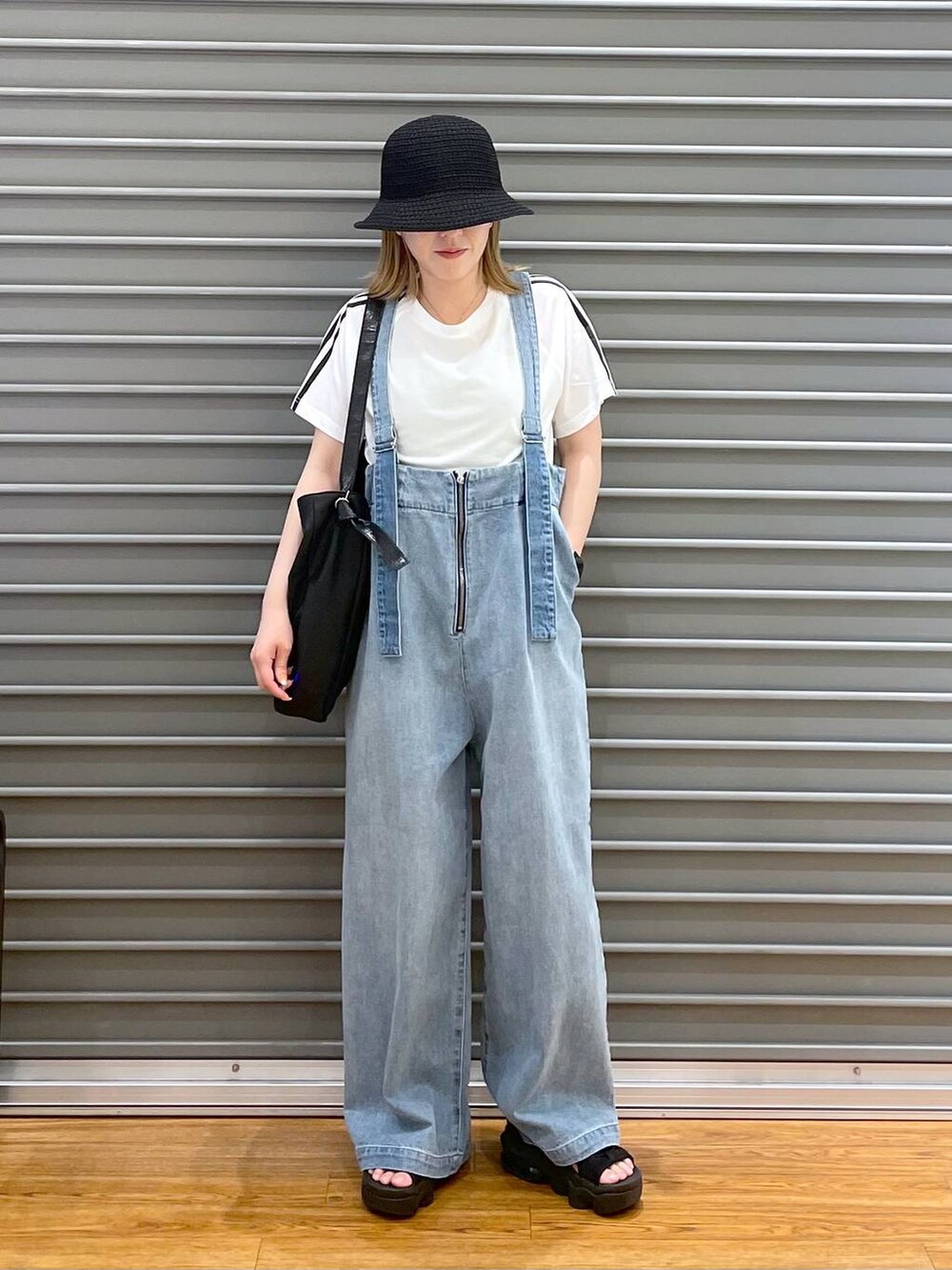 ブルー系のデニムパンツ、ブラック系のショルダーバッグ、ホワイト系のTシャツ/カットソーを着用したレディースの春コーディネートの2枚目の写真
