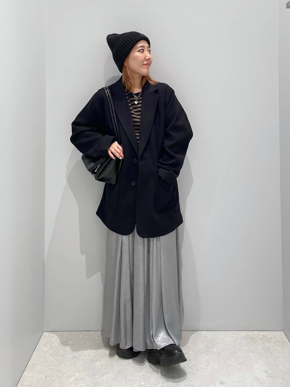 ブラック系のテーラードジャケット、グレー系のスカート、ブラック系のショルダーバッグを着用したレディースの冬コーディネートの2枚目の写真