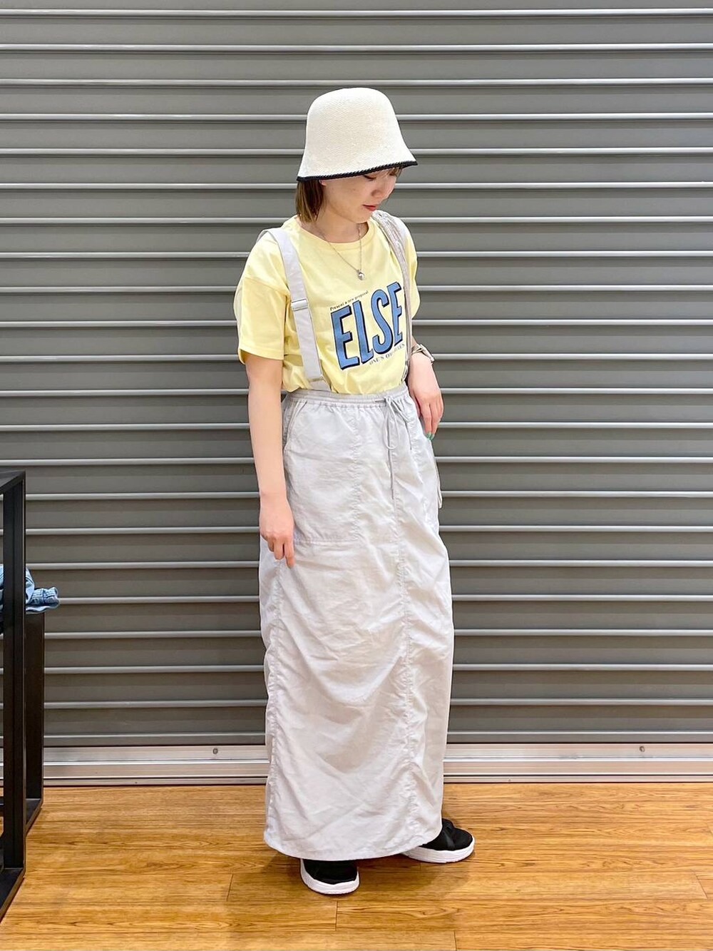 ブラック系のサンダル、グレー系のスカート、イエロー系のTシャツ/カットソーを着用したレディースの春コーディネートの2枚目の写真