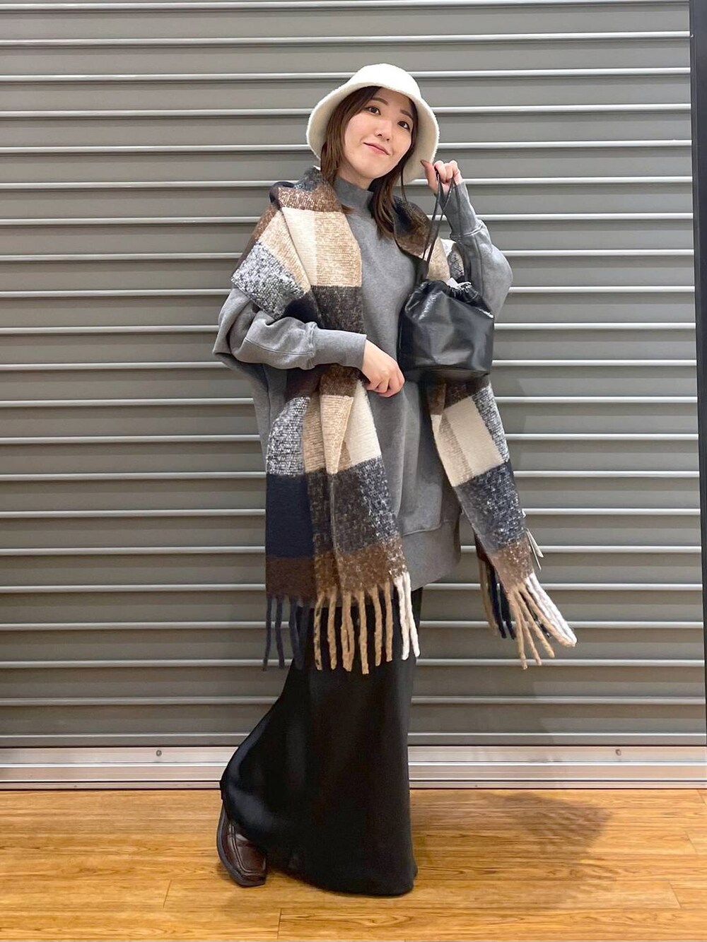 グレー系のチュニック、ブラック系のスカート、ブラック系のショルダーバッグを着用したレディースの冬コーディネートの2枚目の写真