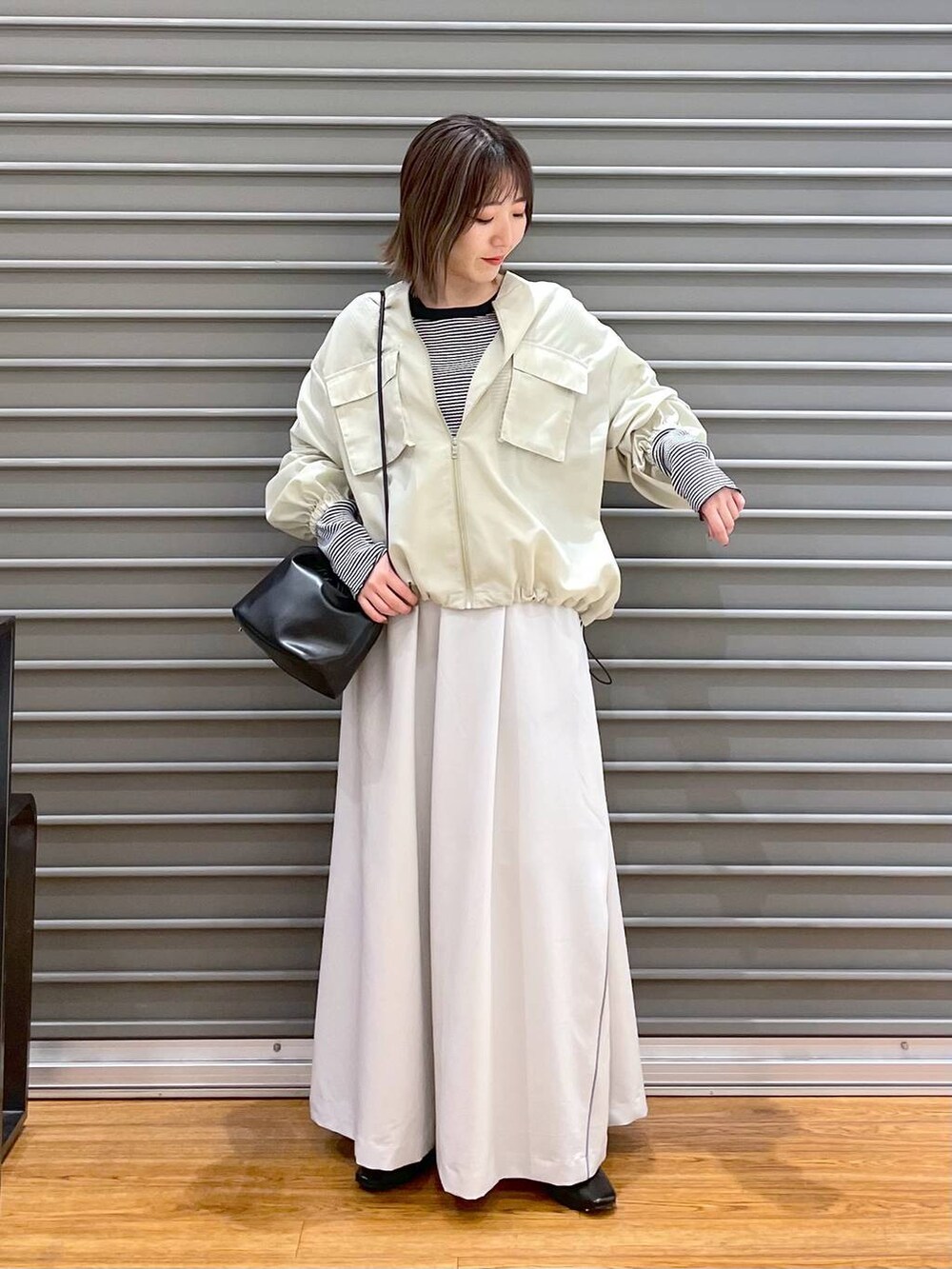 ブラック系のショルダーバッグ、ブラック系のパンプス、ホワイト系のTシャツ/カットソーを着用したレディースの春コーディネートの2枚目の写真