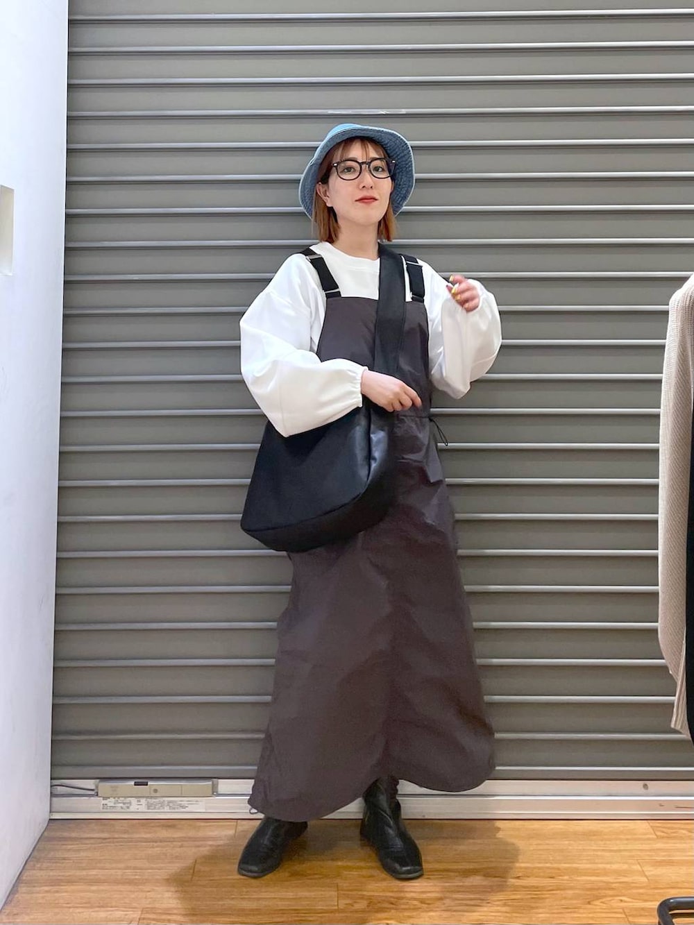 ブラック系のショルダーバッグ、ホワイト系のTシャツ/カットソー、グレー系のジャンパースカートを着用したレディースの春コーディネートの2枚目の写真