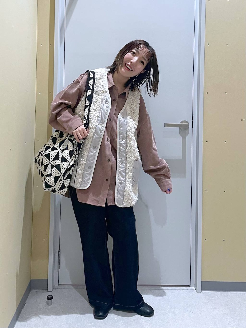 ベージュ系のベスト、ブルー系のデニムパンツ、ピンク系のシャツ/ブラウスを着用したレディースの秋コーディネートの2枚目の写真