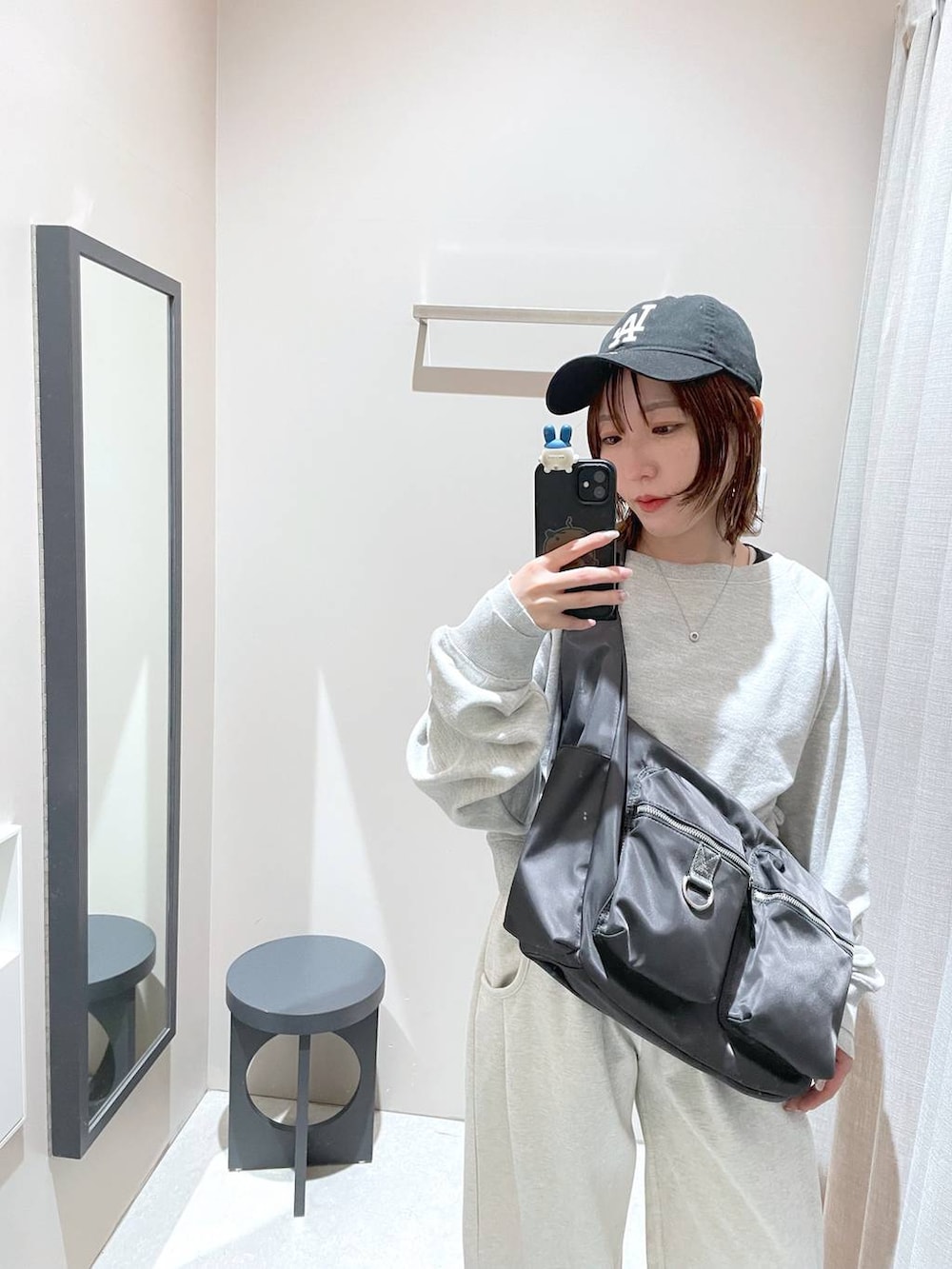 グレー系のショルダーバッグ、グレー系のスウェット、ベージュ系のスウェットパンツを着用したレディースの冬コーディネートの4枚目の写真