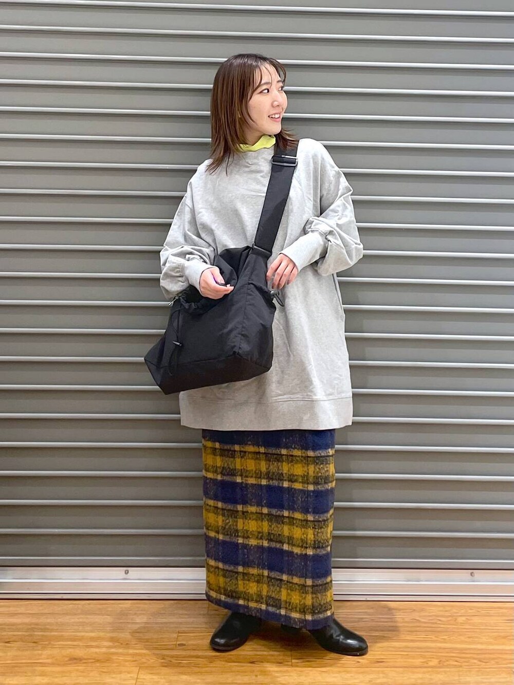 ブルー系のスカート、グレー系のチュニック、ブラック系のブーツを着用したレディースの冬コーディネートの2枚目の写真