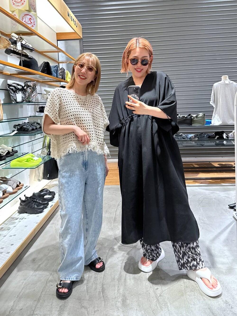 ホワイト系のサンダル、ブラック系のワンピース、ブルー系のデニムパンツを着用したレディースの春コーディネートの2枚目の写真