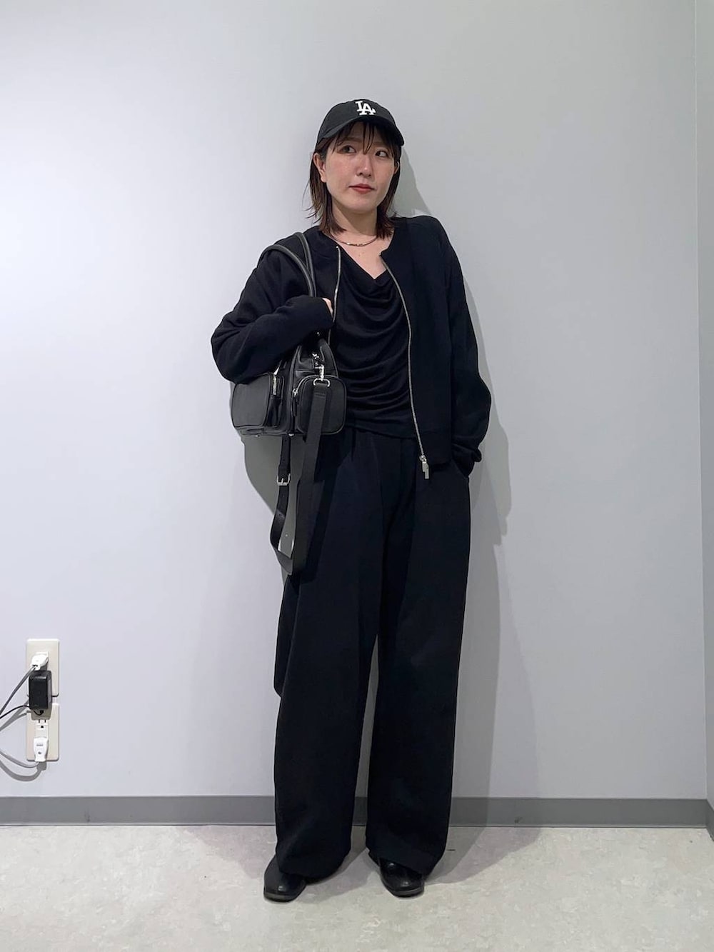 ブラック系のボストンバッグ、ブラック系のTシャツ/カットソー、ブラック系のカーディガン/ボレロを着用したレディースの冬コーディネートの2枚目の写真