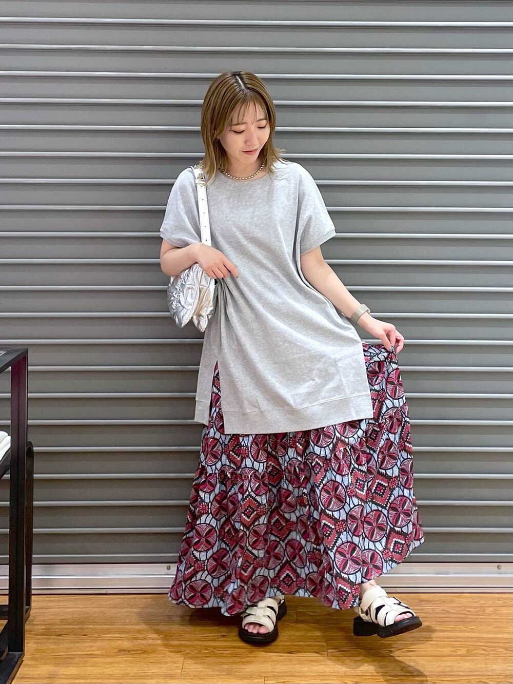 ピンク系のスカート、シルバー系のショルダーバッグ、ホワイト系のサンダルを着用したレディースの夏コーディネートの2枚目の写真