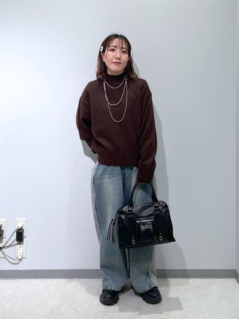 ブラック系のボストンバッグ、ブルー系のデニムパンツ、ブラウン系のニット/セーターを着用したレディースの冬コーディネートの2枚目の写真