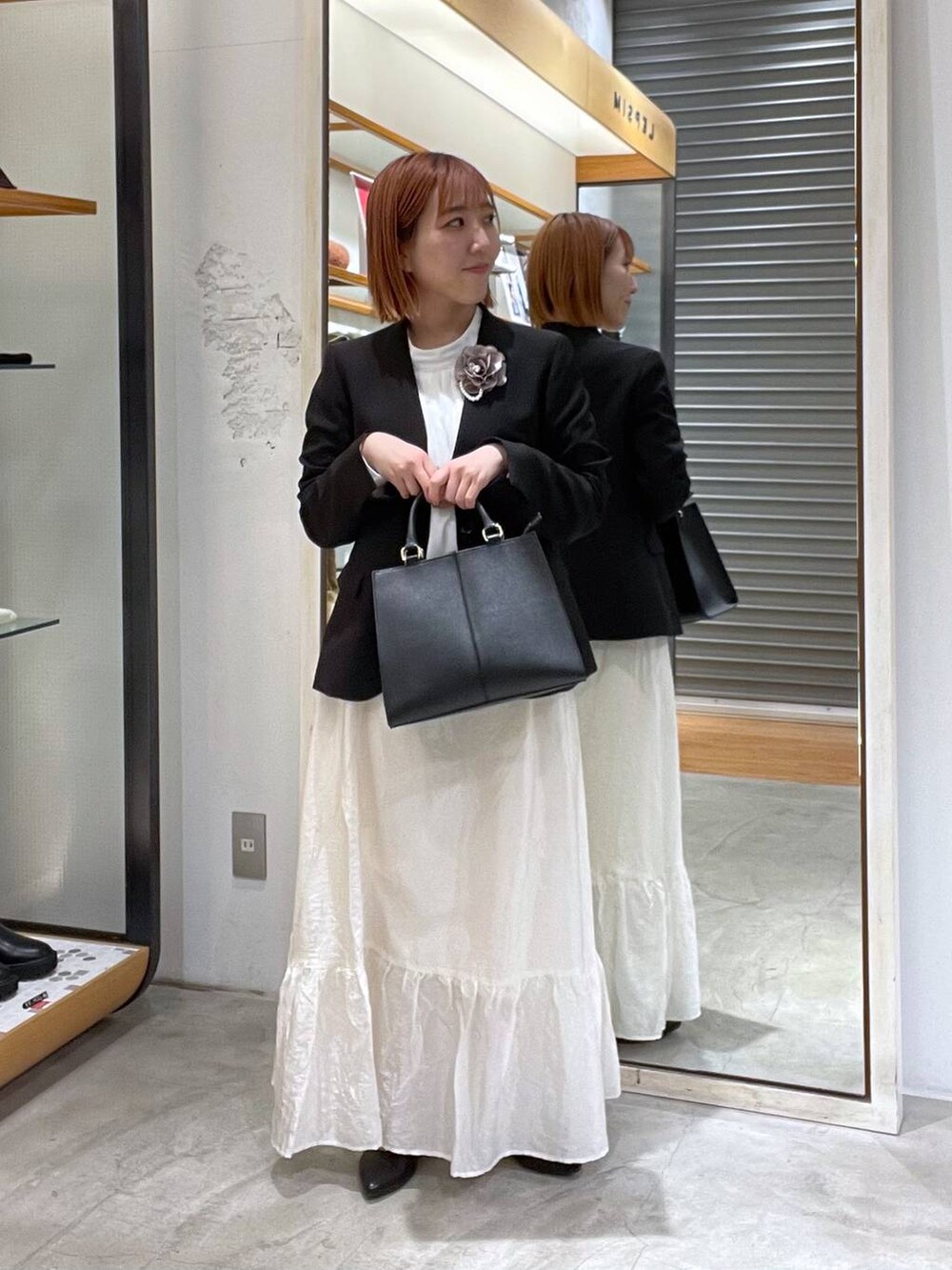 ホワイト系のスカート、ブラック系のノーカラージャケット、ホワイト系のシャツ/ブラウスを着用したレディースの冬コーディネートの2枚目の写真