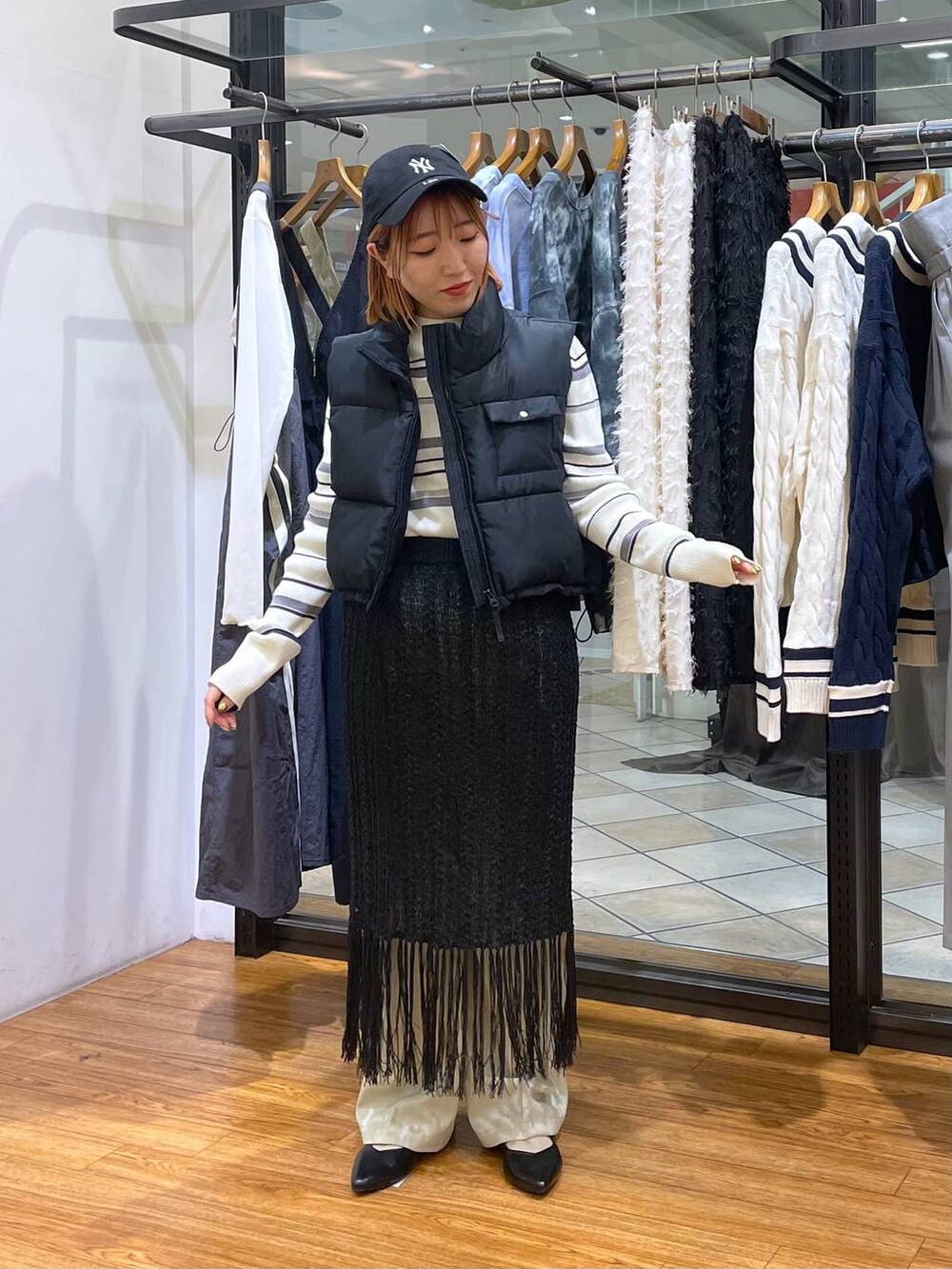 ブラック系のベスト、グリーン系のスラックス、ホワイト系のニット/セーターを着用したレディースの春コーディネートの3枚目の写真