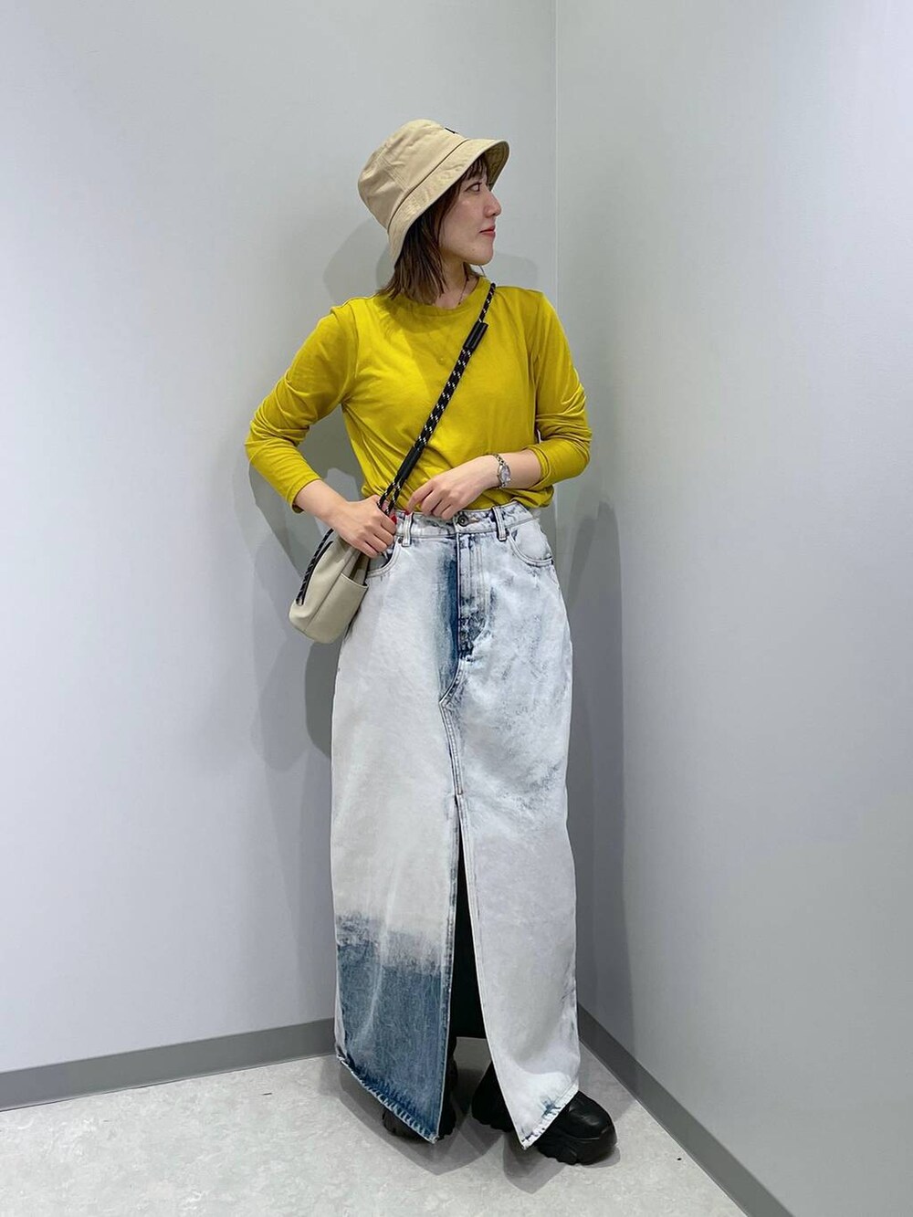 グレー系のショルダーバッグ、ブルー系のデニムスカート、イエロー系のTシャツ/カットソーを着用したレディースの秋コーディネートの3枚目の写真