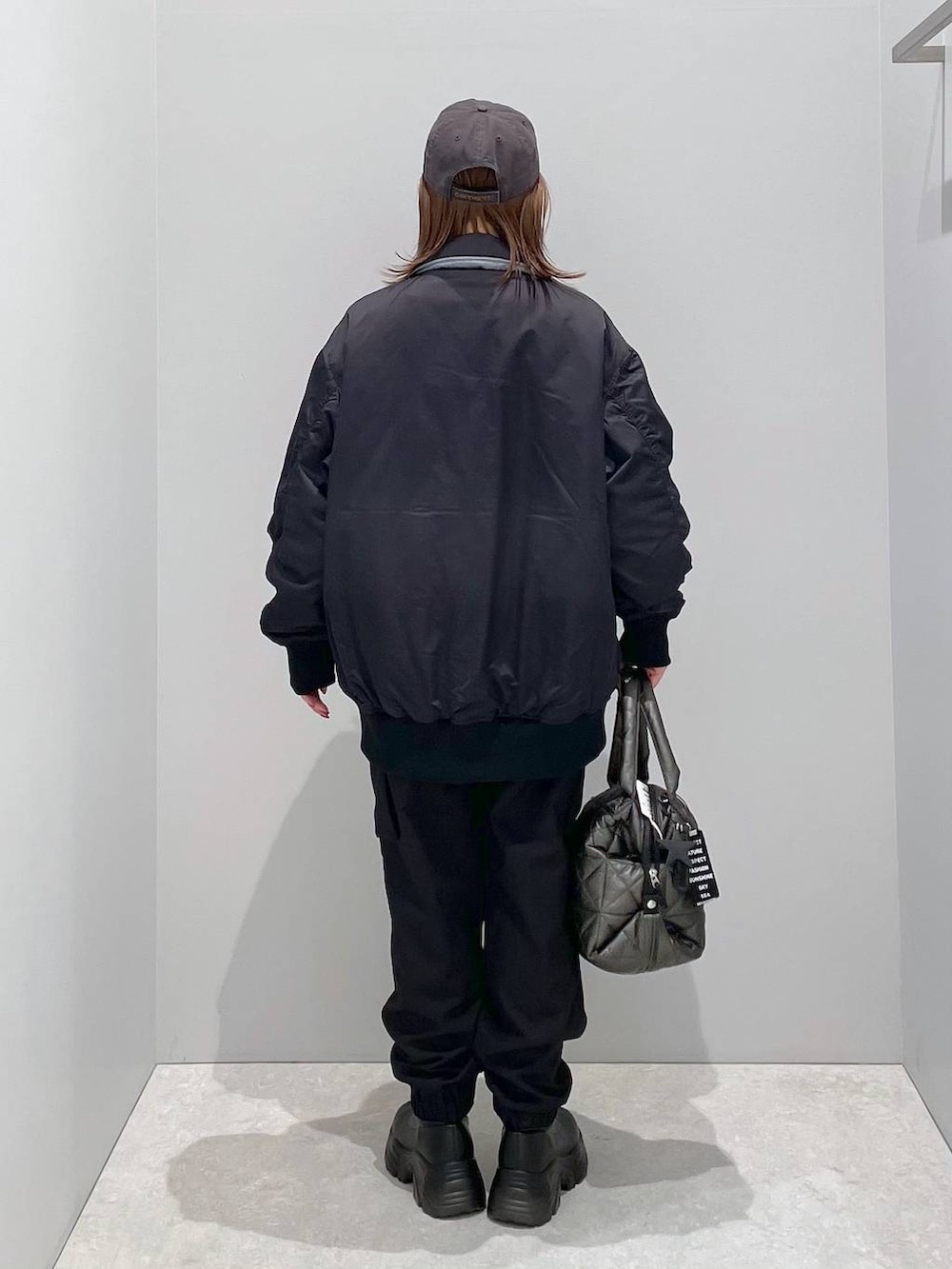 ブラック系のブルゾン、ブラック系のトートバッグ、ブラック系のカーゴパンツを着用したレディースの冬コーディネートの3枚目の写真