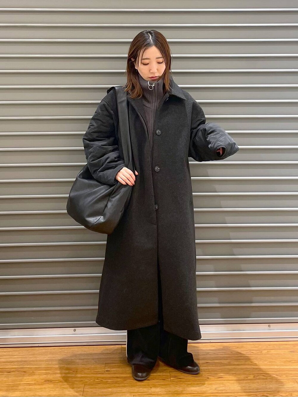 ブラック系のショルダーバッグ、ブラウン系のブーツ、グレー系のニット/セーターを着用したレディースの冬コーディネートの3枚目の写真