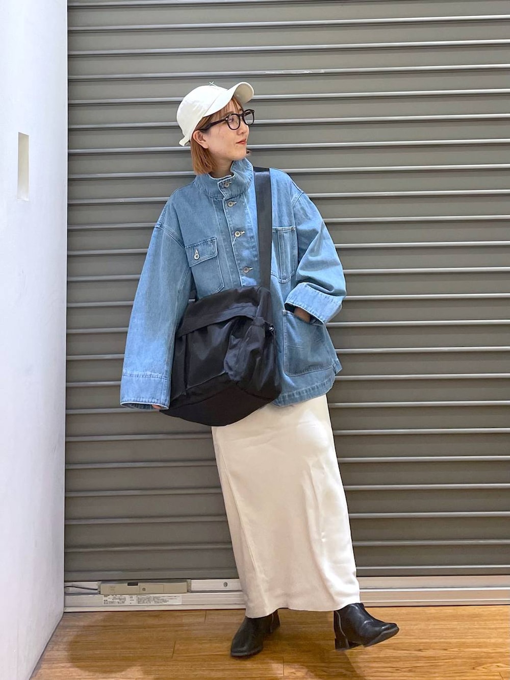 ホワイト系のスカート、ブラック系のショルダーバッグ、ブルー系のデニムジャケットを着用したレディースの春コーディネートの4枚目の写真