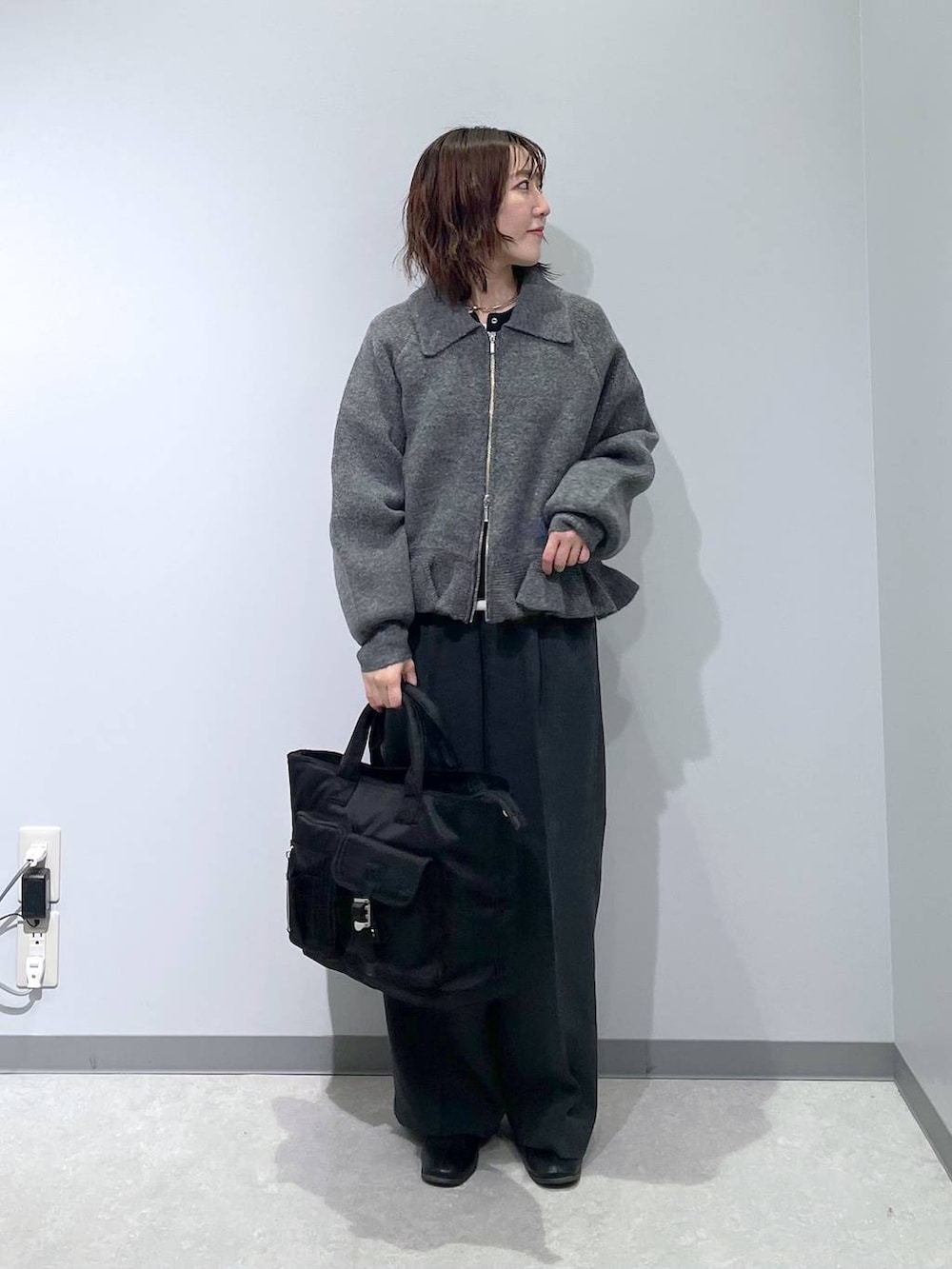 ブラック系のトートバッグ、グレー系のブルゾンを着用したレディースの冬コーディネートの2枚目の写真