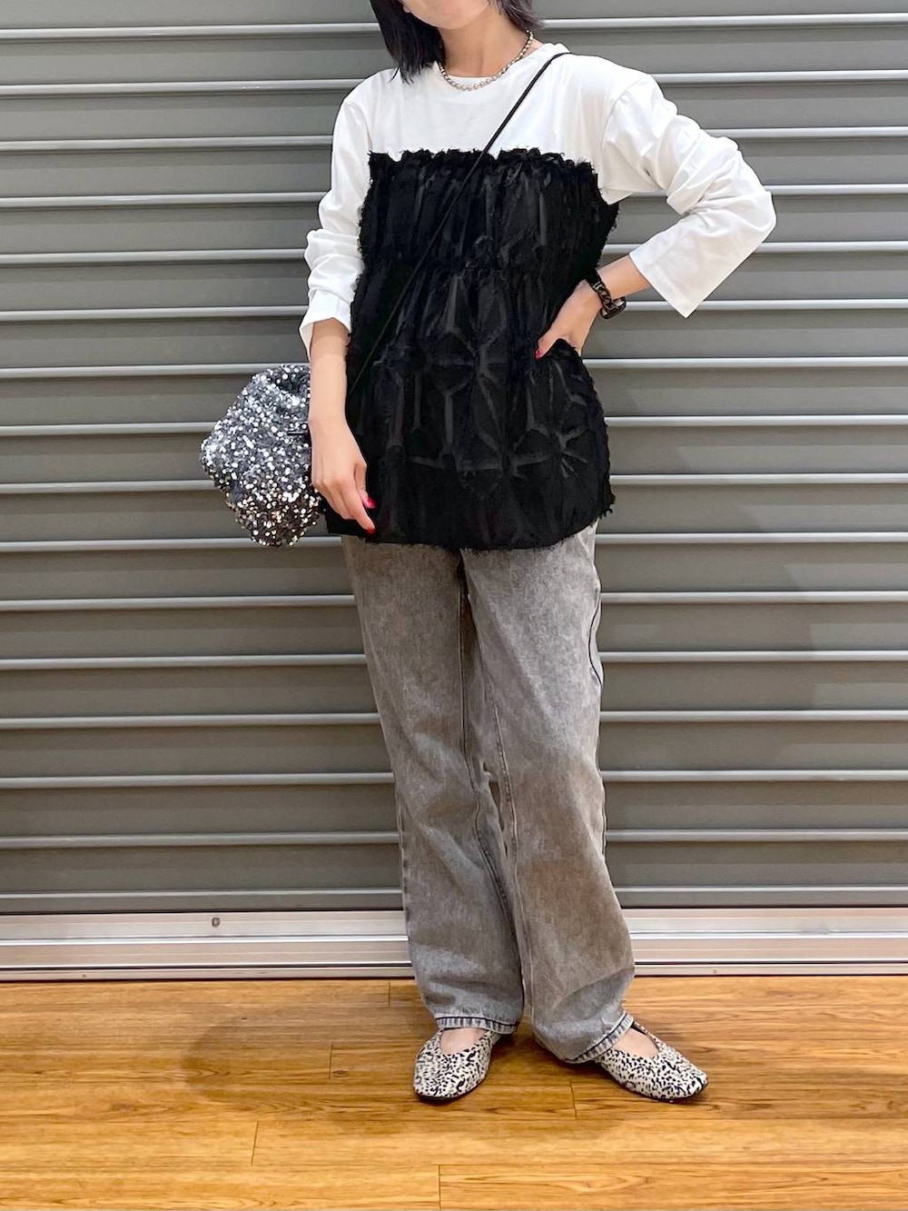 シルバー系のショルダーバッグ、ホワイト系のパンプス、グレー系のデニムパンツを着用したレディースの秋コーディネートの2枚目の写真