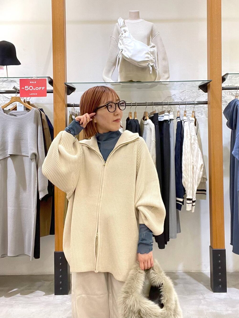 グレー系のハンドバッグ、ホワイト系のニット/セーター、ブラック系のパンプスを着用したレディースの冬コーディネートの4枚目の写真