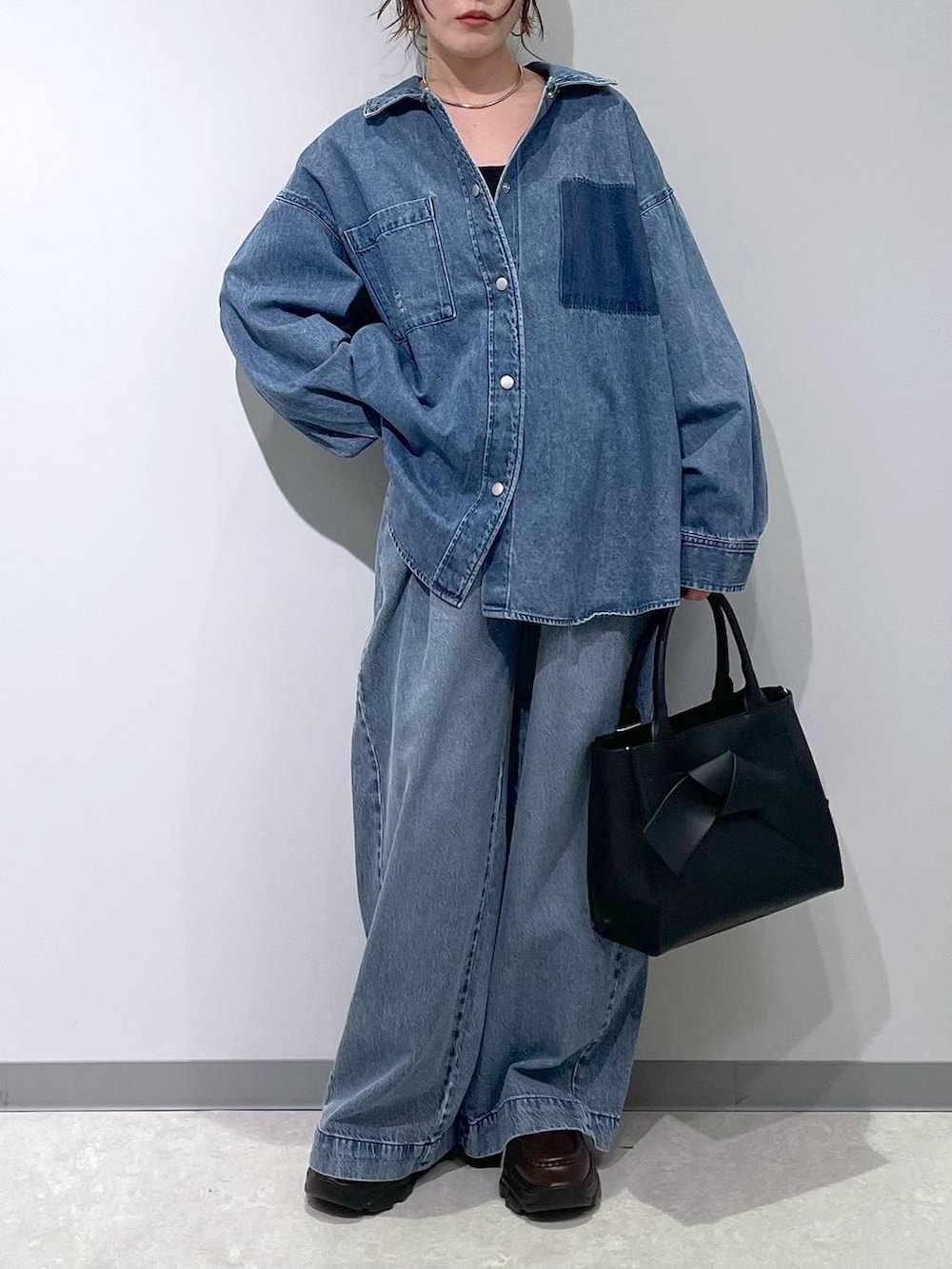 ブルー系のデニムパンツ、ブラック系のハンドバッグ、ブラウン系のローファーを着用したレディースの冬コーディネートの3枚目の写真