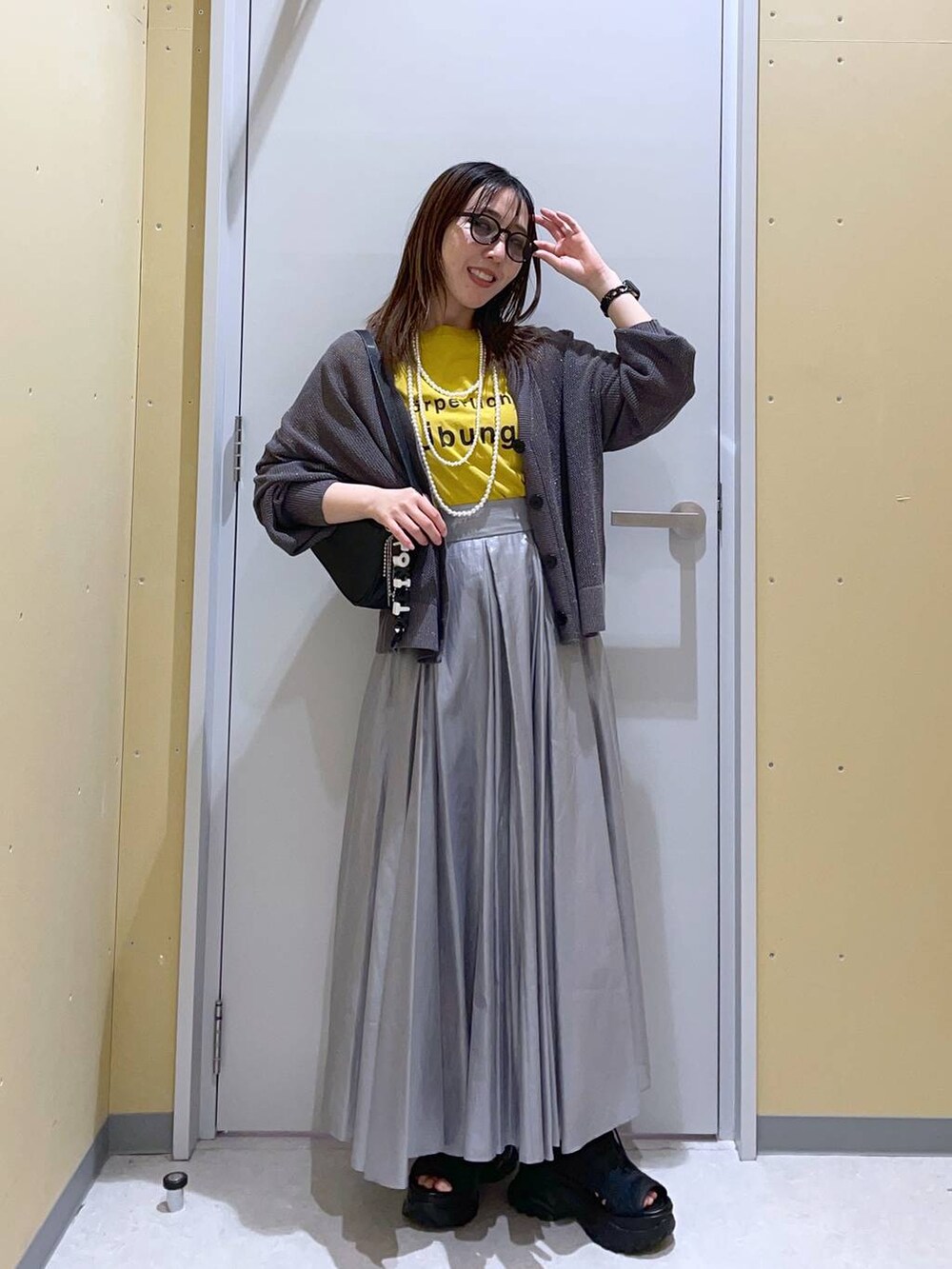 ブラック系のトートバッグ、グレー系のカーディガン/ボレロ、ブラック系のサンダルを着用したレディースの春コーディネートの2枚目の写真