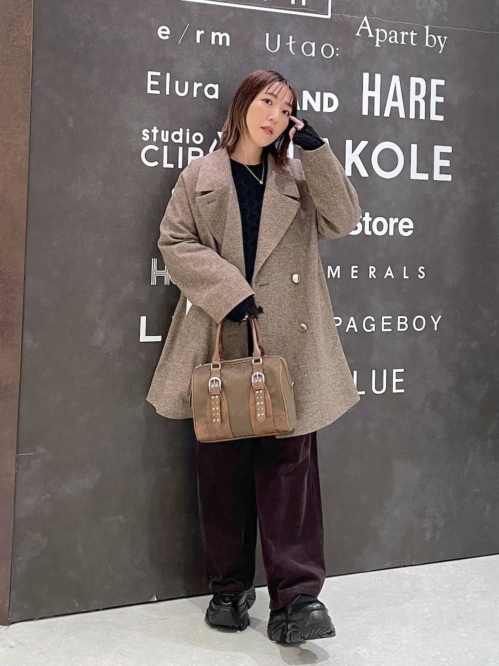 ブラック系のブーツ、ブラウン系のチェスターコート、ブラウン系のその他パンツを着用したレディースの秋コーディネートの2枚目の写真