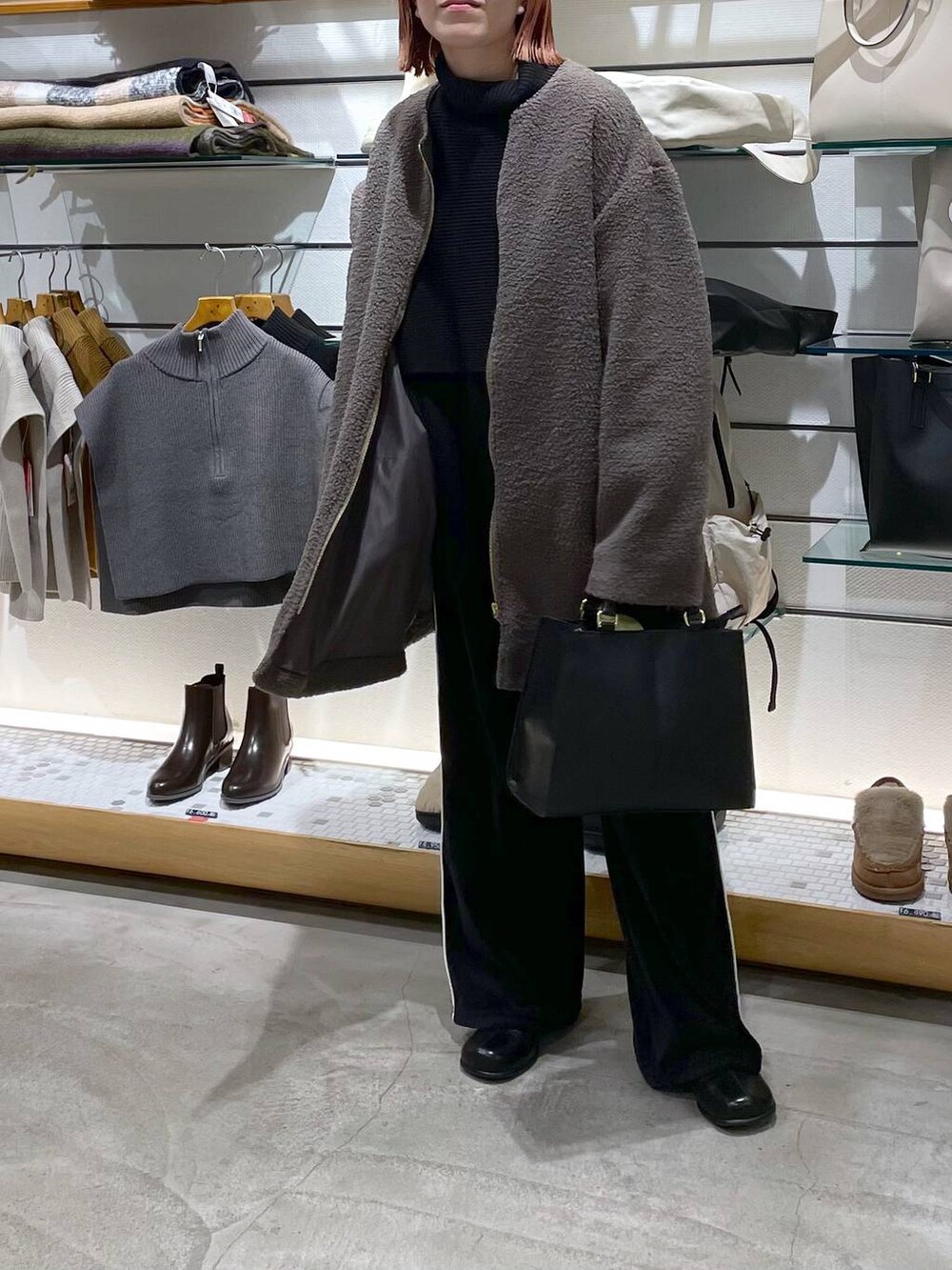 ブラック系のニット/セーター、ブラウン系のノーカラーコート、ブラック系のブーツを着用したレディースの冬コーディネートの3枚目の写真