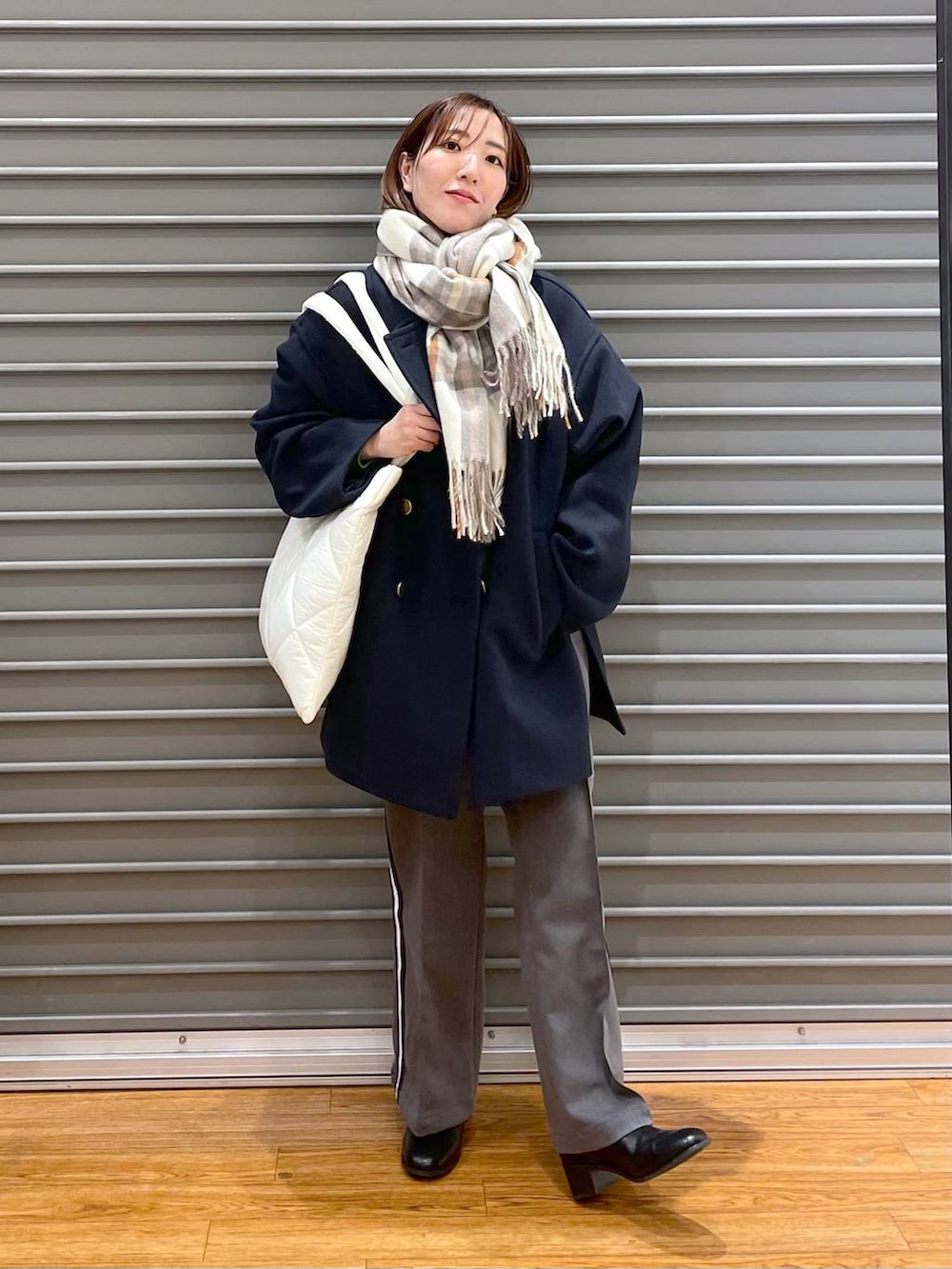 ブラック系のブーツ、ホワイト系のトートバッグ、グレー系のその他パンツを着用したレディースの秋コーディネートの3枚目の写真