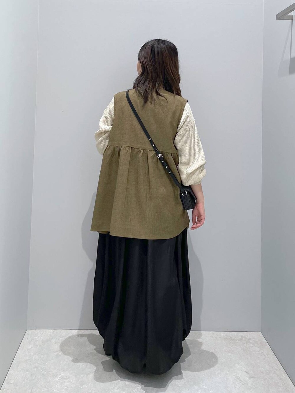 ホワイト系のニット/セーター、ブラウン系のベスト、ブラック系のショルダーバッグを着用したレディースの春コーディネートの3枚目の写真