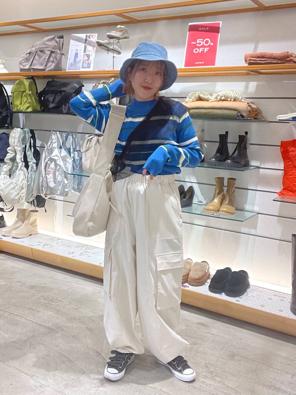 ホワイト系のショルダーバッグ、ホワイト系のカーゴパンツ、ブルー系のニット/セーターを着用したレディースの春コーディネートの3枚目の写真