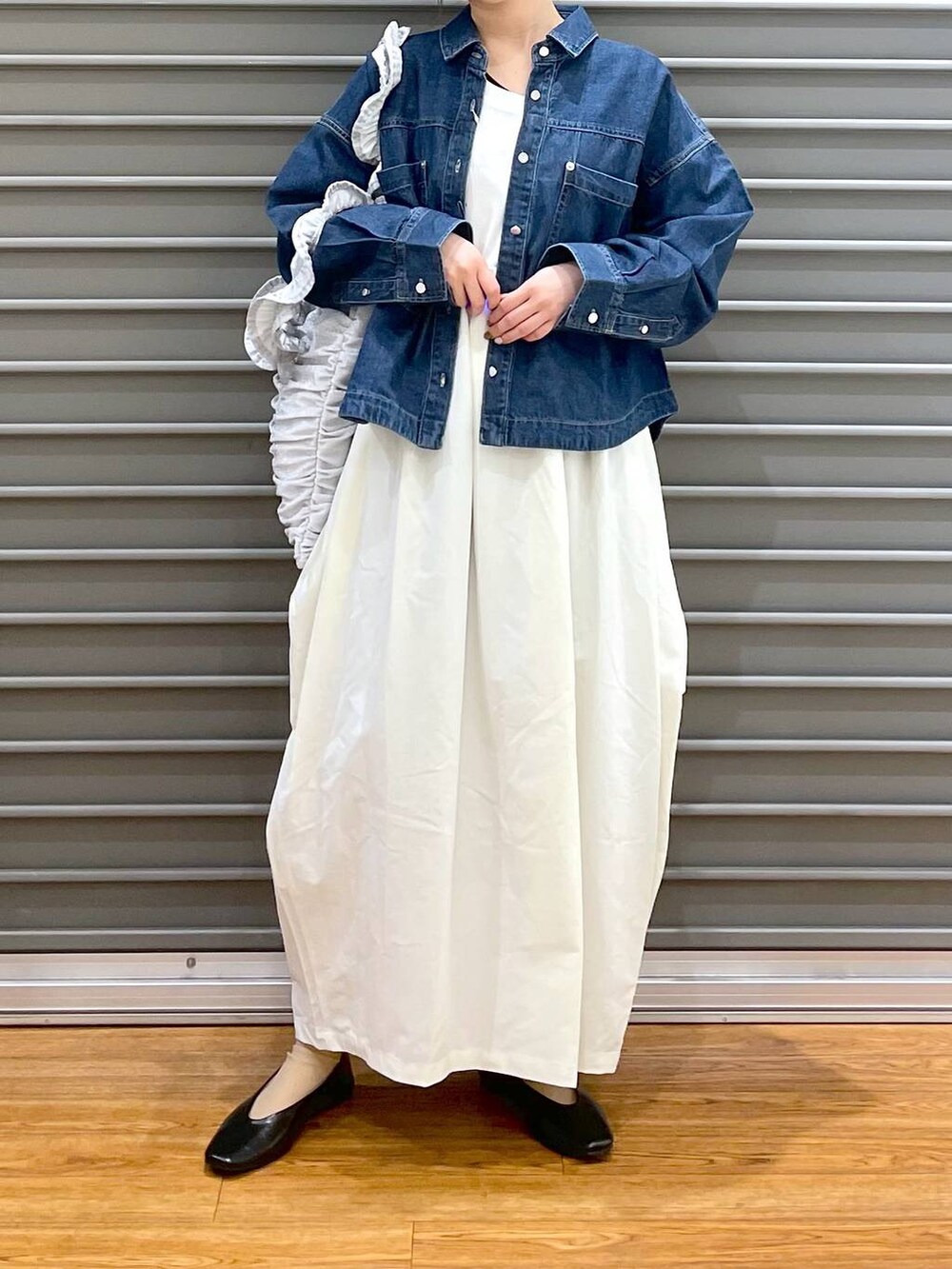 シルバー系のトートバッグ、ブラック系のパンプス、ブルー系のシャツ/ブラウスを着用したレディースの春コーディネートの2枚目の写真