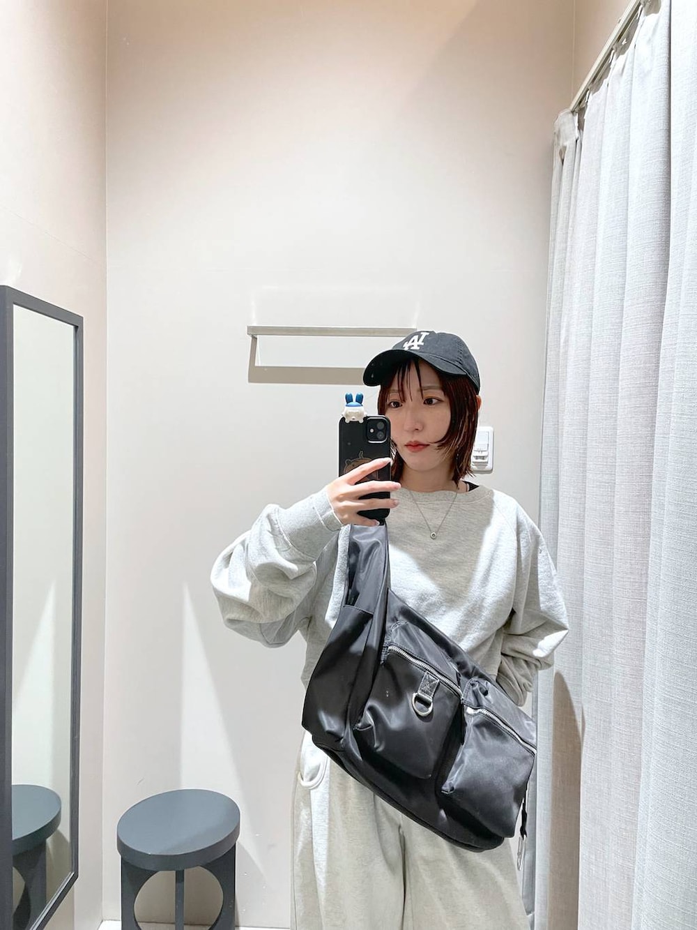 グレー系のショルダーバッグ、グレー系のスウェット、ベージュ系のスウェットパンツを着用したレディースの冬コーディネートの7枚目の写真