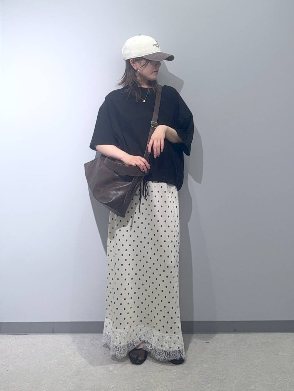 ブラウン系のショルダーバッグ、ブラック系のTシャツ/カットソー、ホワイト系のスカートを着用したレディースの夏コーディネートの4枚目の写真