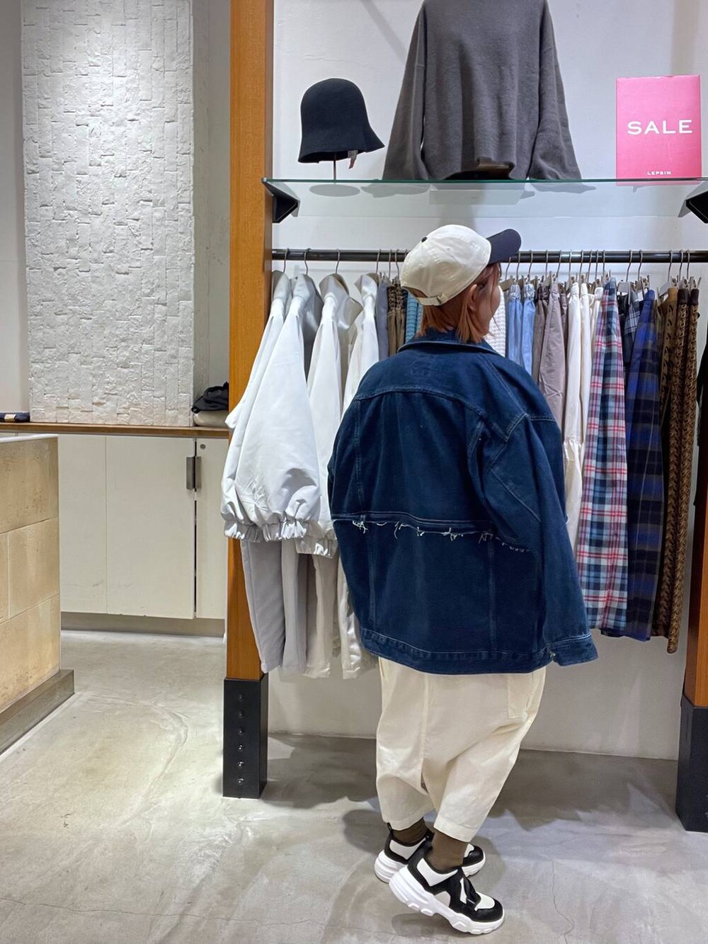 オレンジ系のスウェット、ブルー系のデニムジャケット、ホワイト系のスニーカーを着用したレディースの冬コーディネートの5枚目の写真