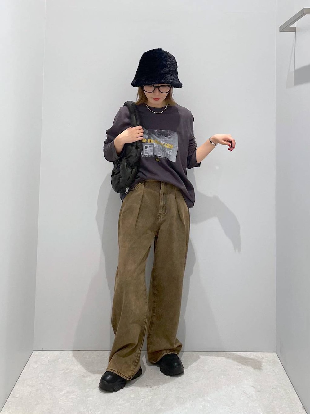 ブラック系のハンドバッグ、ブラウン系のデニムパンツ、グレー系のTシャツ/カットソーを着用したレディースの秋コーディネートの2枚目の写真