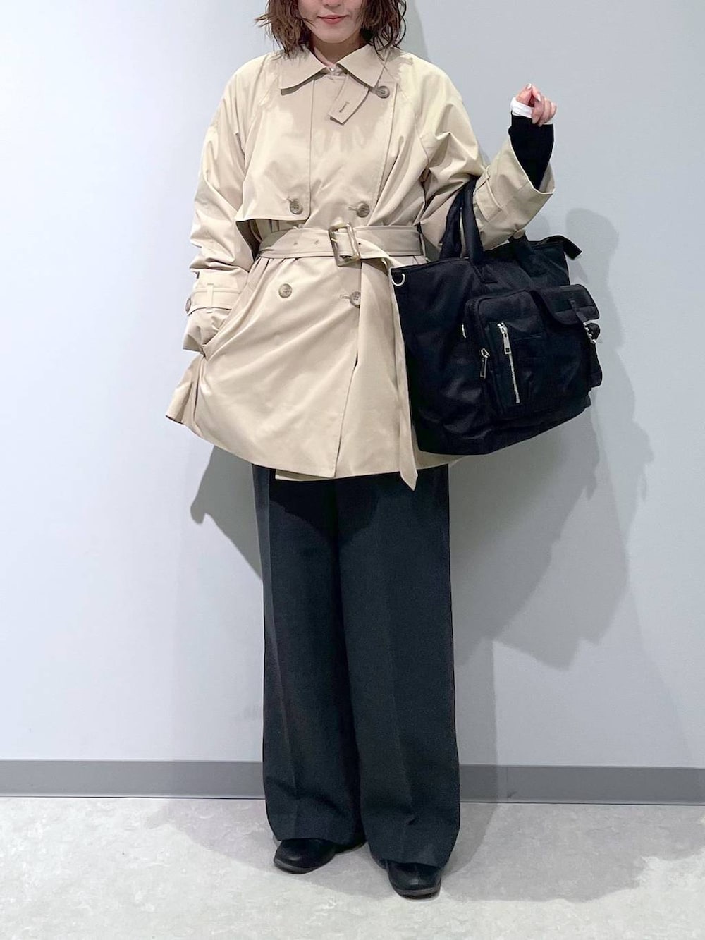 ベージュ系のトレンチコート、ブラック系のトートバッグを着用したレディースの冬コーディネートの2枚目の写真
