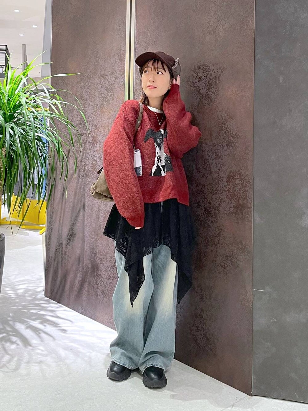 ブルー系のデニムパンツ、ブラウン系のショルダーバッグ、レッド系のニット/セーターを着用したレディースの秋コーディネートの3枚目の写真