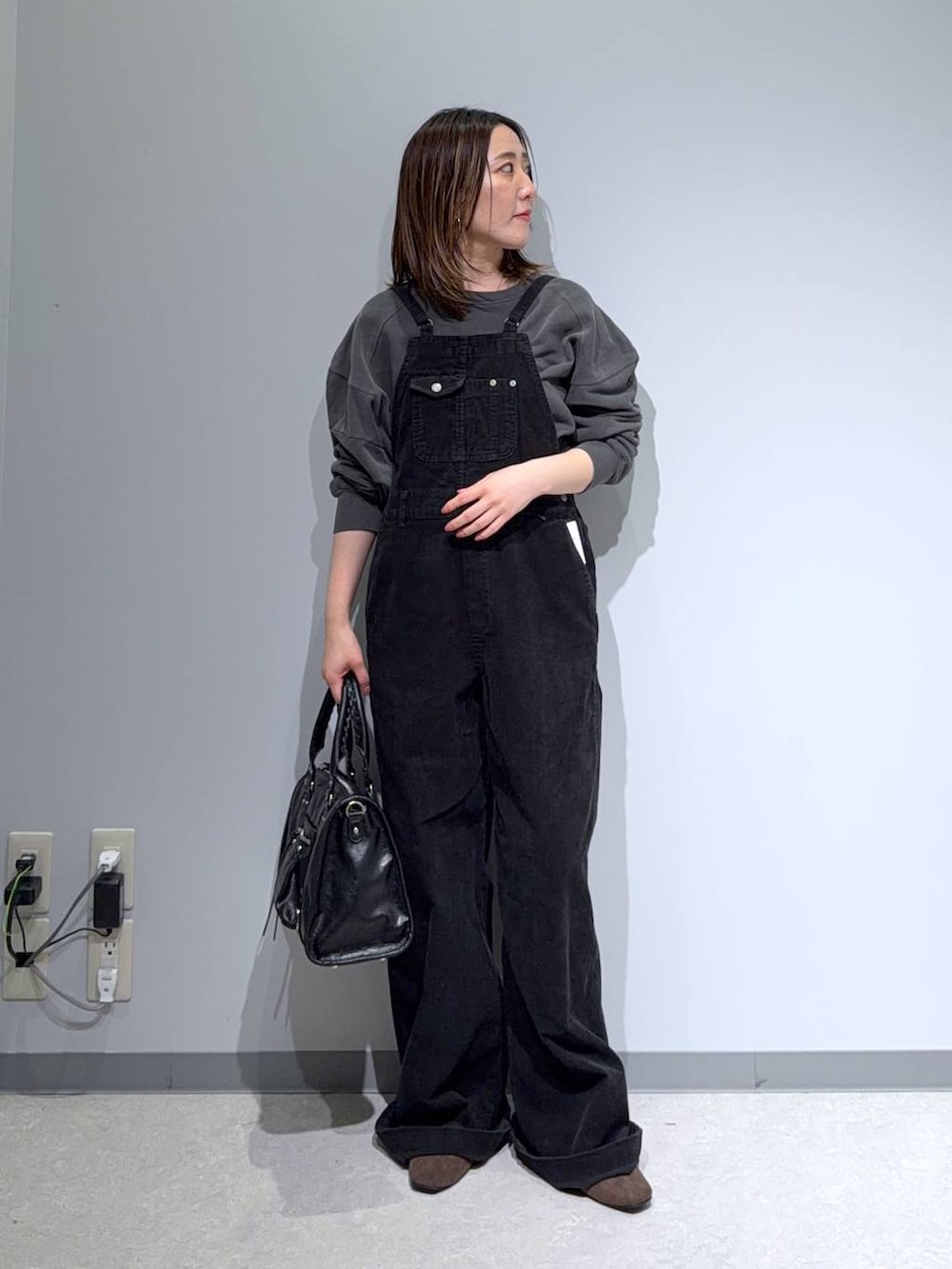 グレー系のサロペット/オーバーオール、グレー系のスウェット、ブラウン系のパンプスを着用したレディースの秋コーディネートの3枚目の写真